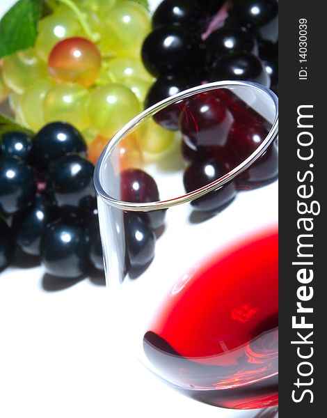 A glass of red wine and grapes on a white background. A glass of red wine and grapes on a white background