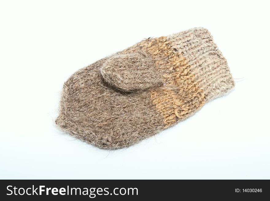 Knitted mitten from a rough wool on a white background