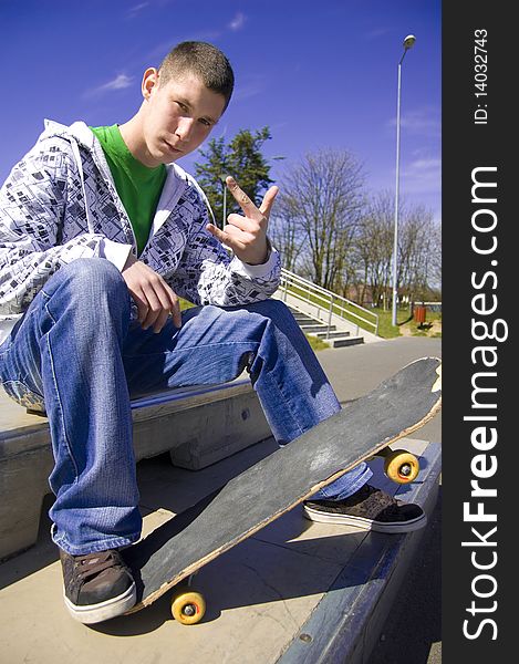 Teenage skateboarder conceptual image. Teenage skateboarder sits in skatepark.