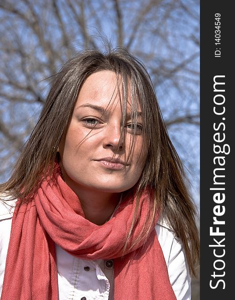 Portrait of a young beautiful girl in a red scarf. Outdoor scene. Close up.