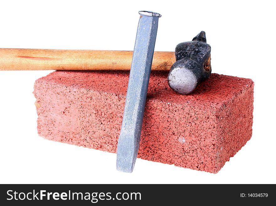 Building materials and tools: a chisel and a hammer with a brick from red clay.