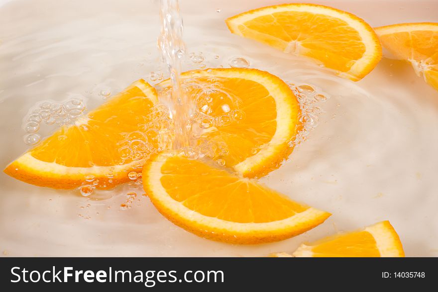 Orange slices under flowing water - concept of refreshment