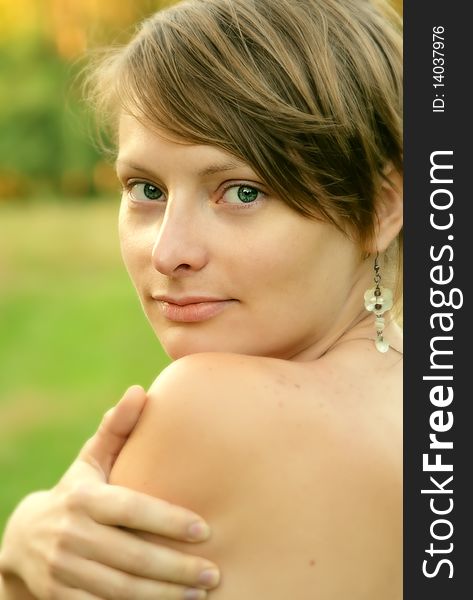 Close up of a young woman looking at you with hand lying on her shoulder. Close up of a young woman looking at you with hand lying on her shoulder