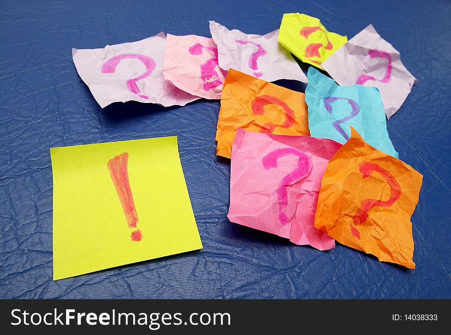 Sticker notes with exclamation and question signs over blue leather background. Sticker notes with exclamation and question signs over blue leather background