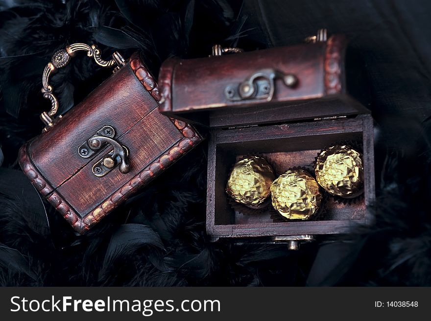 Three sweets in mini small treasure chest next to closed chest. Three sweets in mini small treasure chest next to closed chest