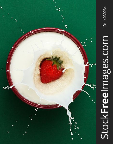 Strawberry dropped into bowl of milk, creating a splash sculpture. Strawberry dropped into bowl of milk, creating a splash sculpture