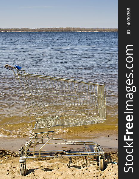 Trolley from the supermarket on the sand by the river. Trolley from the supermarket on the sand by the river