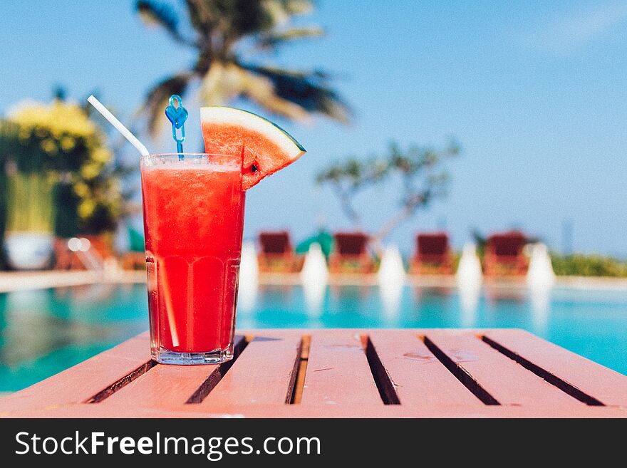 Healthy concept, Water melon smoothie on a wood table with swimming pool and blue sky background.