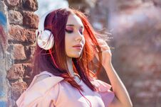 Gorgeous Redheads Lady Listening Music In Headphones On Blurred Outdoor Background And Wall Bricks Royalty Free Stock Photography Gorgeous Redheads Lady Listening Music In Headphones On Blurred Outdoor Background And Wall Bricks Royalty Free Stock Photography