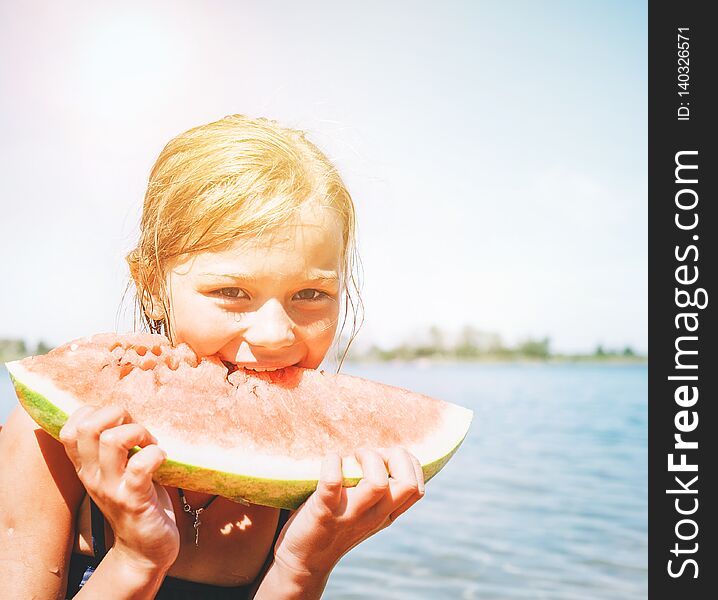 Little smiling Girl eating red watermelon portrait on the beach