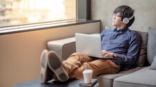 Asian Man Sitting On Sofa Looking Out Of Window Stock Images