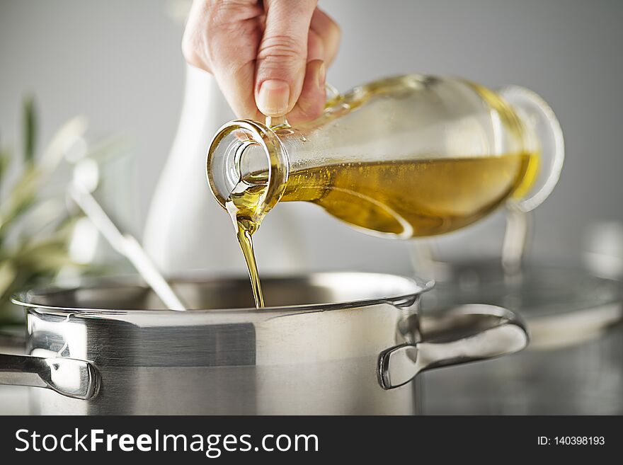 Cooking meal in a pot. Bottle of Extra virgin oil pouring in to pot for cooking meal. Healthy food concept. Cooking meal in a pot. Bottle of Extra virgin oil pouring in to pot for cooking meal. Healthy food concept