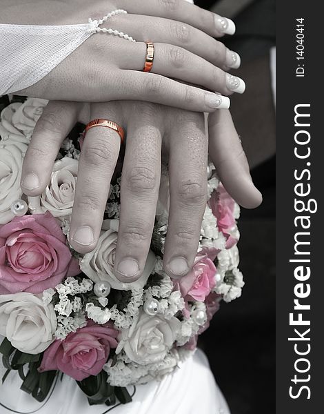 Hands of the bride and the groom
with gold rings on the  wedding bouquet. Hands of the bride and the groom
with gold rings on the  wedding bouquet