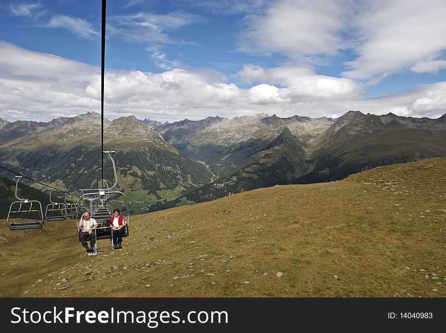Two senior hiker sitting on chair lift going uphill with beautiful mountain panorama of Lienzer Dolomites in Tyrol, Austria. Two senior hiker sitting on chair lift going uphill with beautiful mountain panorama of Lienzer Dolomites in Tyrol, Austria.