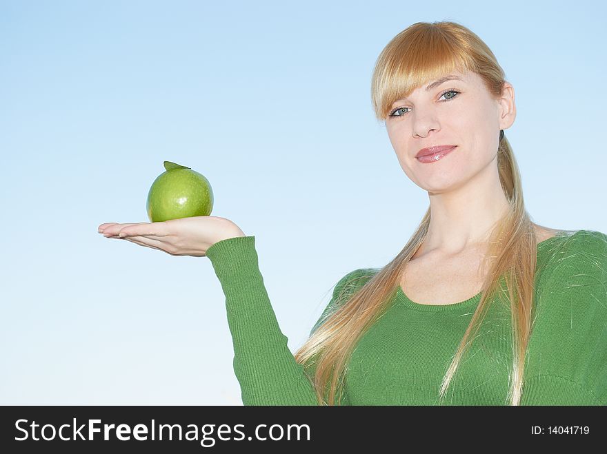 Green apple in a hand on a background of the sky. Green apple in a hand on a background of the sky
