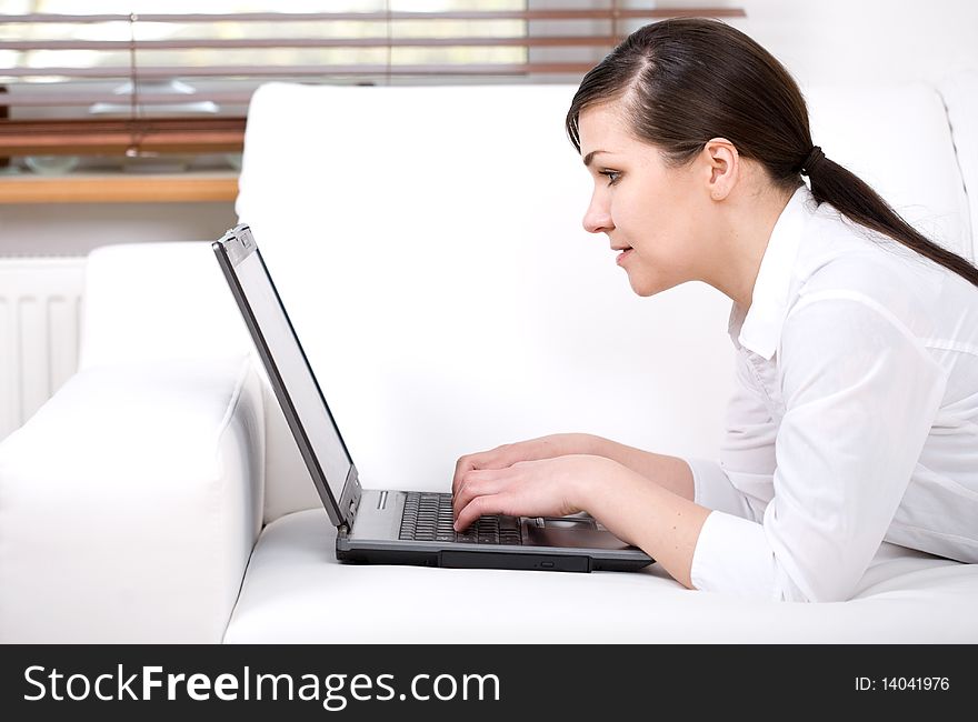 Happy attractive young woman at sofa with laptop. Happy attractive young woman at sofa with laptop