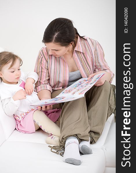 Mother and daughter reading book on sofa. Mother and daughter reading book on sofa