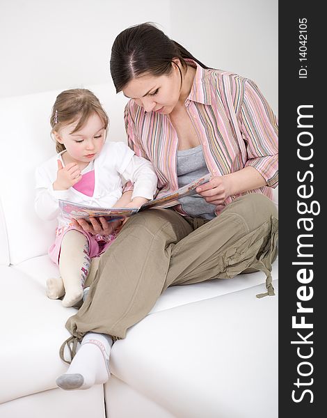 Mother and daughter reading book on sofa. Mother and daughter reading book on sofa
