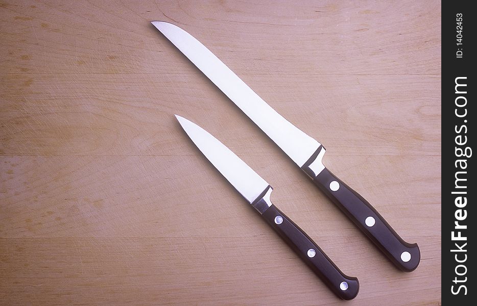 Two kitchen knives on a wooden chopping board