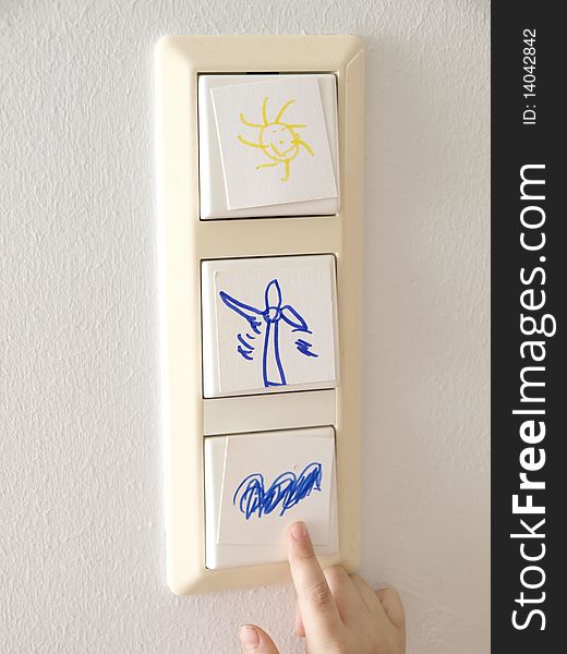 Light switch with alternative energy symbols and a childÂ´s hand. Light switch with alternative energy symbols and a childÂ´s hand