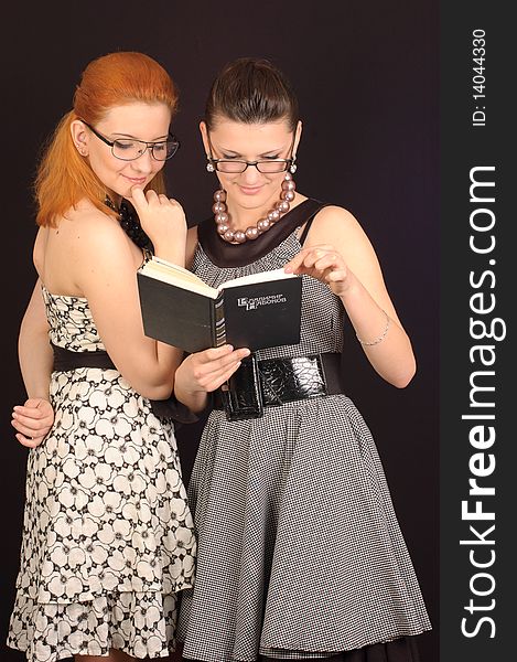 Two girls in dresses in retro style on a black background in studio