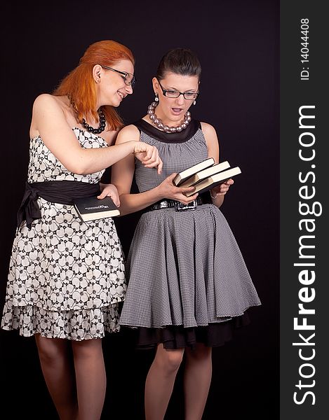 Two girls in dresses in retro style on a black background in studio