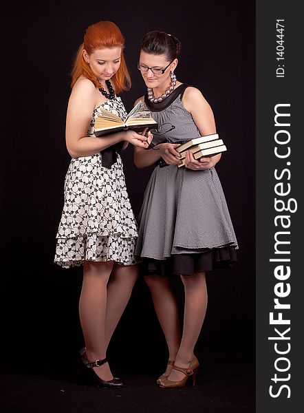 Two girls in dresses in retro style on a black background in studio