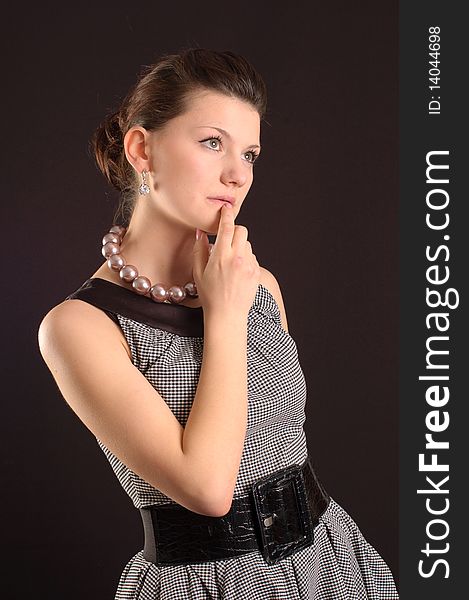 Portrait of a girl with beads in a dress in retro style on a black background