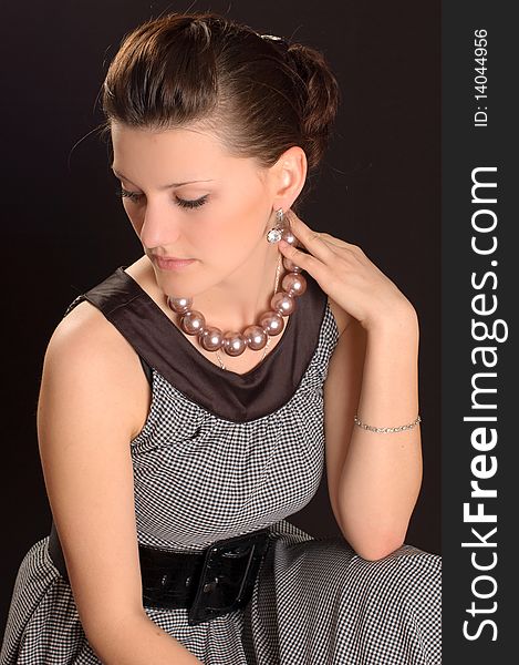 Portrait of a girl with beads in a dress in retro style on a black background