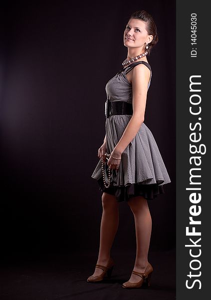 Portrait of a girl with beads in a dress in retro style on a black background