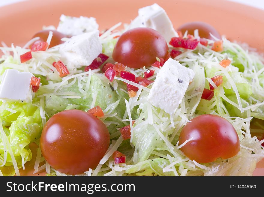 Fresh salad with feta and tomatoes on orange plate