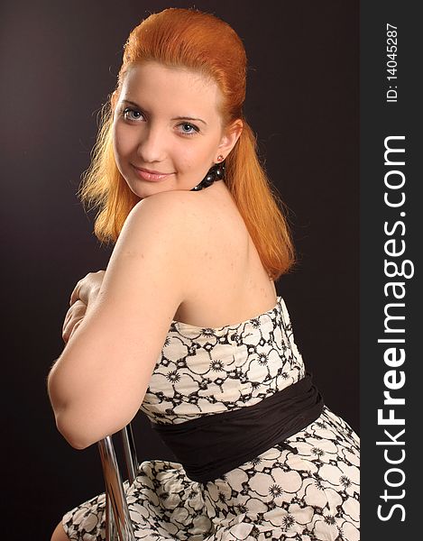 Red-haired woman in a dress in a retro style on a black background