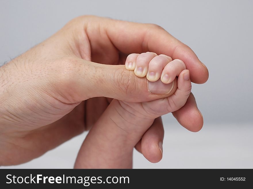 Handle of the baby clenching the thumb of the father