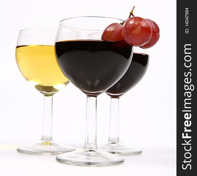 Red and white wine in wineglasses with three red grapes on white background