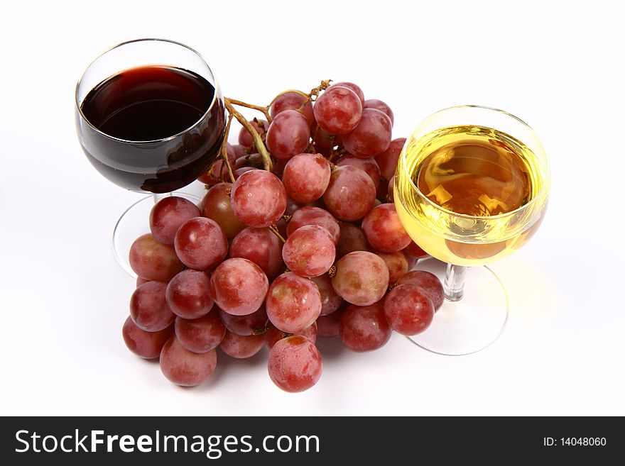 Two glasses of white and red wine and red grapes on white background