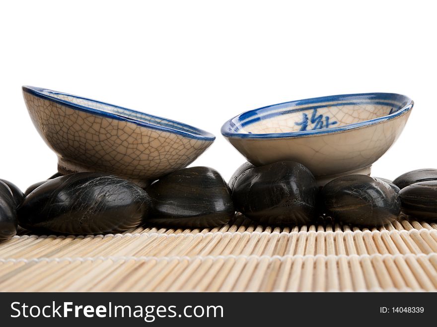 Two cups and stones on mat  isolated in white