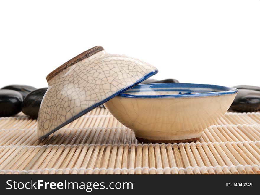 Two tea clay cups and stones on mat  isolated in white