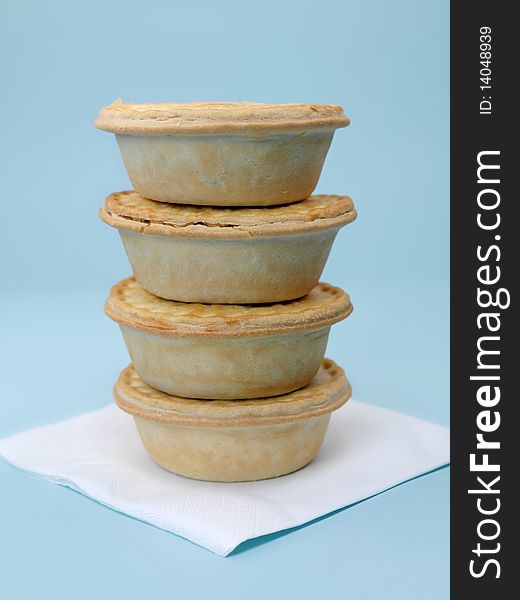 A stack of Australian meat pies isolated against a blue background