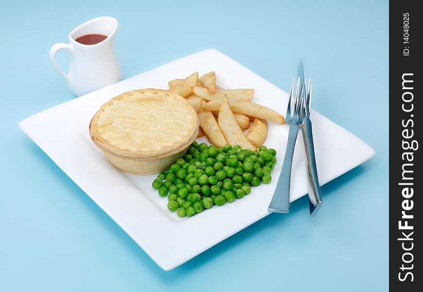 An Australian meat pie served with peas and chips isolated against a blue background