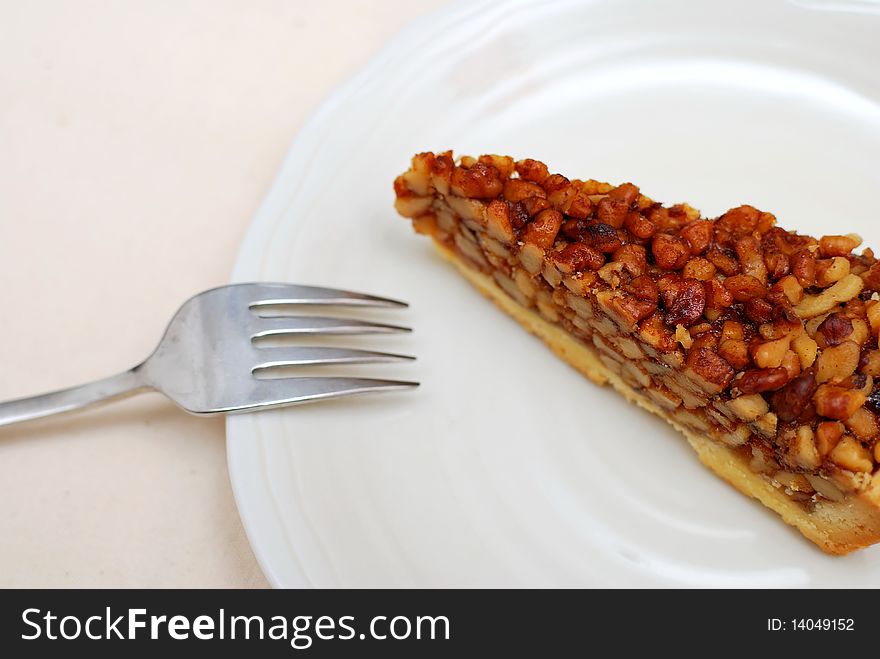 A single slice of hazel nut tart on white plate. For concepts such as food and beverage, diet and nutrition, and healthy eating.