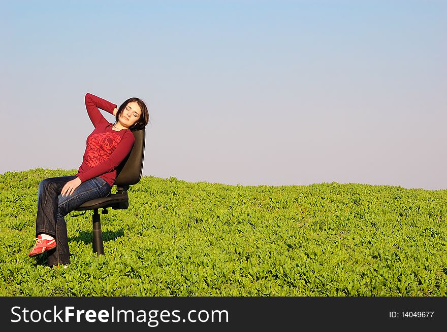 Girl in a spring field on a chair. Girl in a spring field on a chair