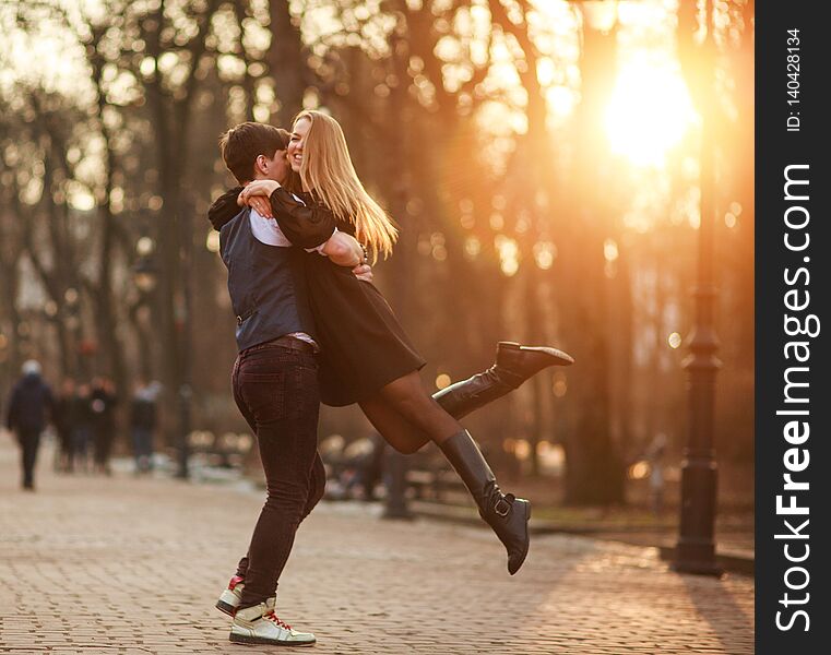 Elegant young couple in love in a classic style passionately dancing in the city park at sunset. Elegant young couple in love in a classic style passionately dancing in the city park at sunset