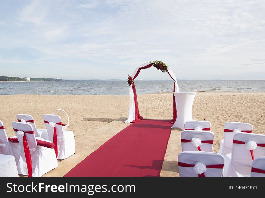 Arch for on-site registration is decorated with flowers and white cloth. Wedding ceremony on the Bay