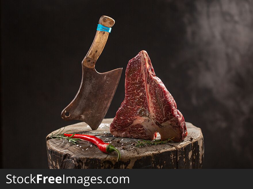 Raw Fresh Marbled Meat Beef ax on a stump on black background