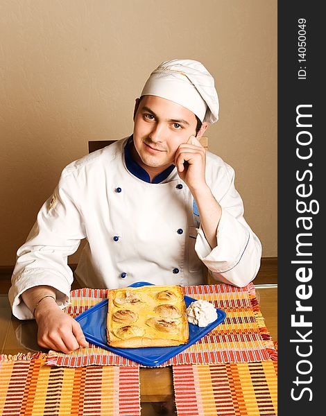 Handsome young chef in the living room with cake o