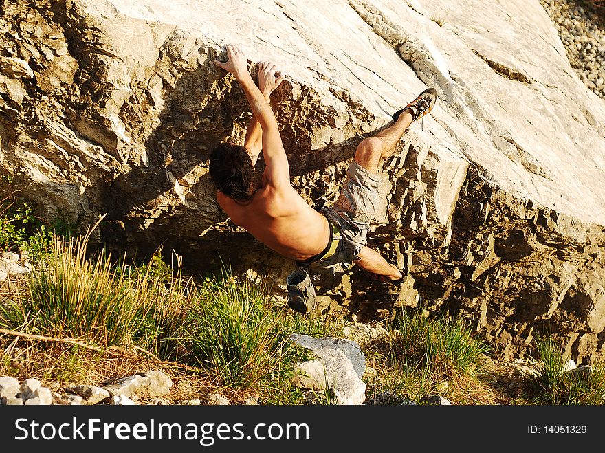 Climber trying to climb the edge of a boulder