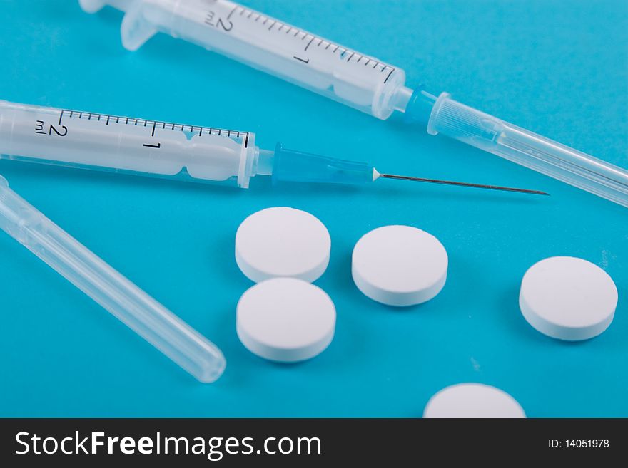 Tablets and syringes on a blue background