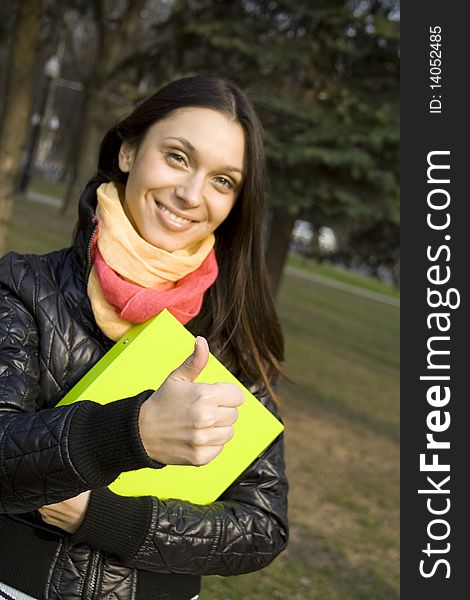 Young beautiful elegant woman walking in the park with folders documents. Thumb sign OK. Young beautiful elegant woman walking in the park with folders documents. Thumb sign OK