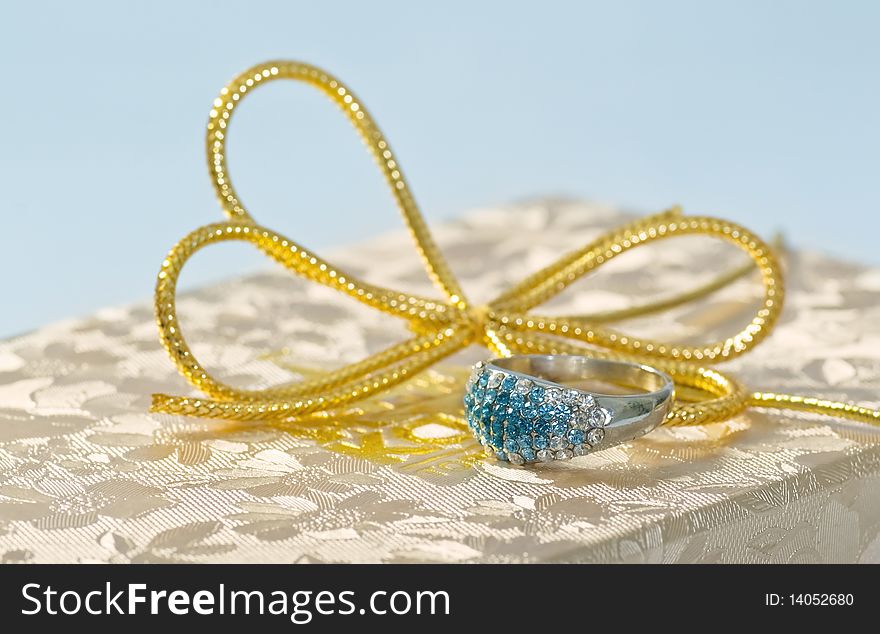 Silver ring on a gift box and a gold bow