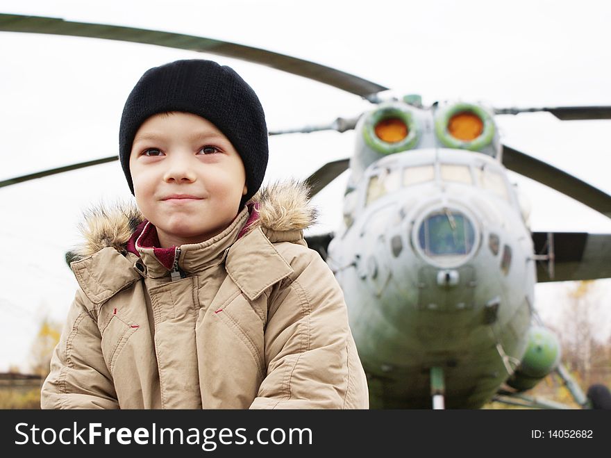 Young boy standing in front of single helicopter and dreaming about flying. Young boy standing in front of single helicopter and dreaming about flying